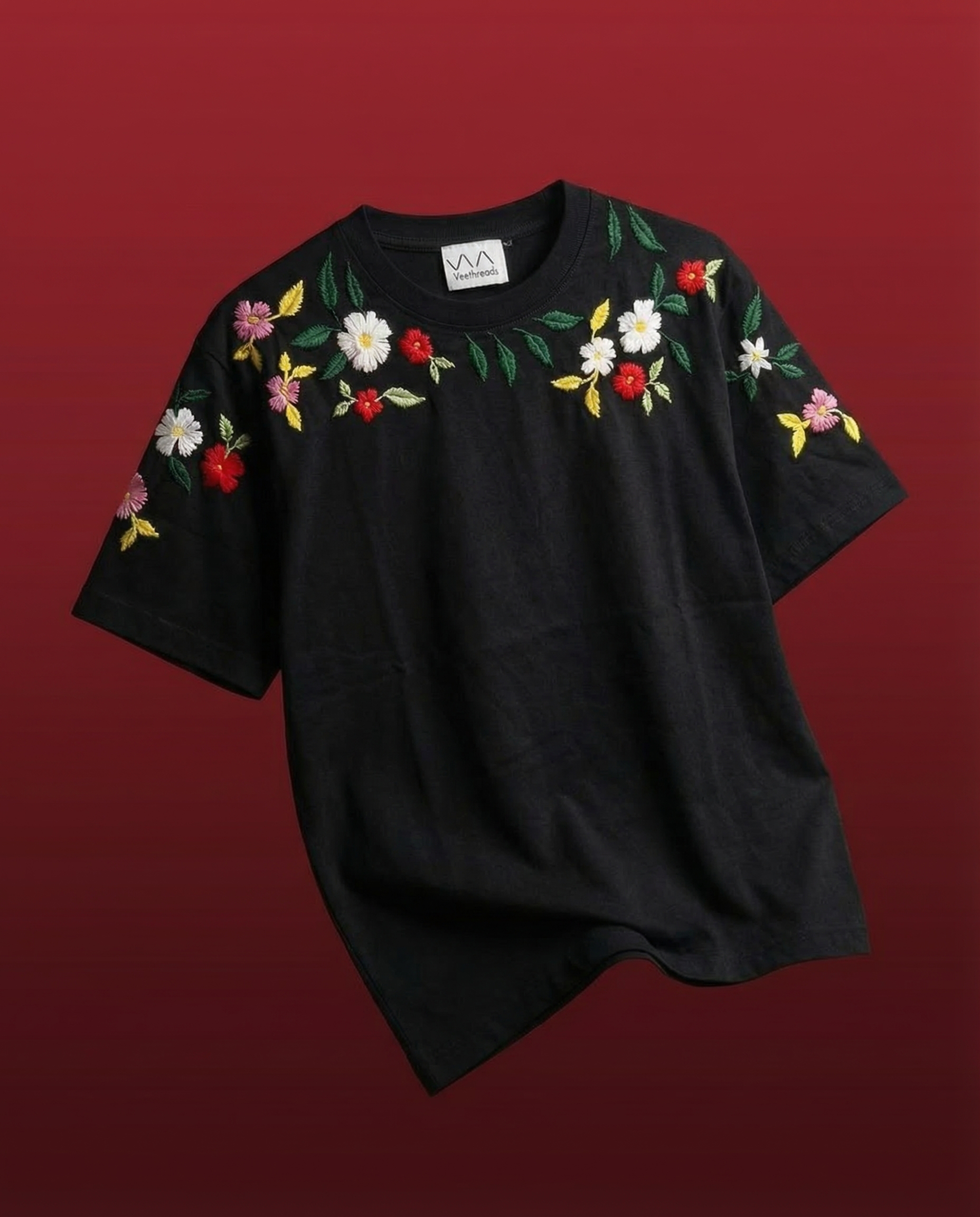Black t-shirt with floral embroidery on a red background