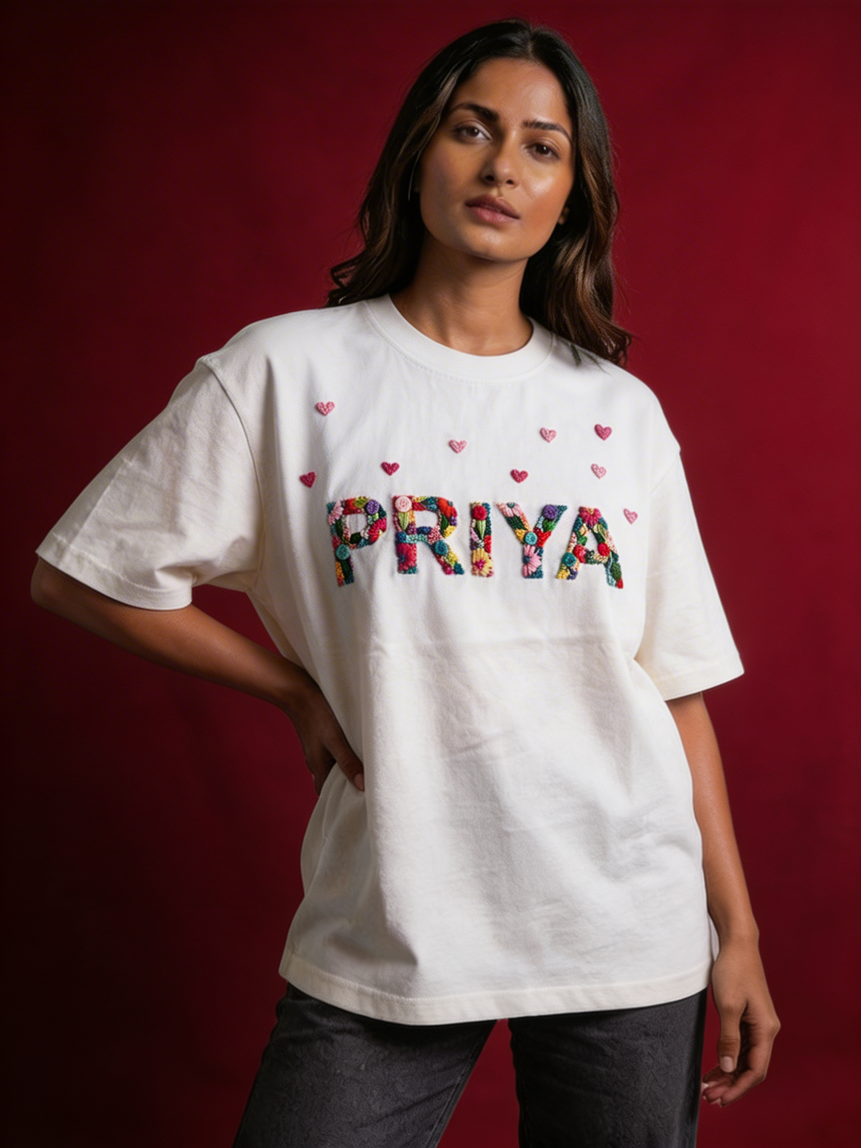 Custom name with little hearts hand-embroidered on a 220 GSM cotton oversized tee — personalised lettering in real thread, made to order.