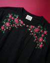 Black t-shirt with pink rose floral embroidery on a red background