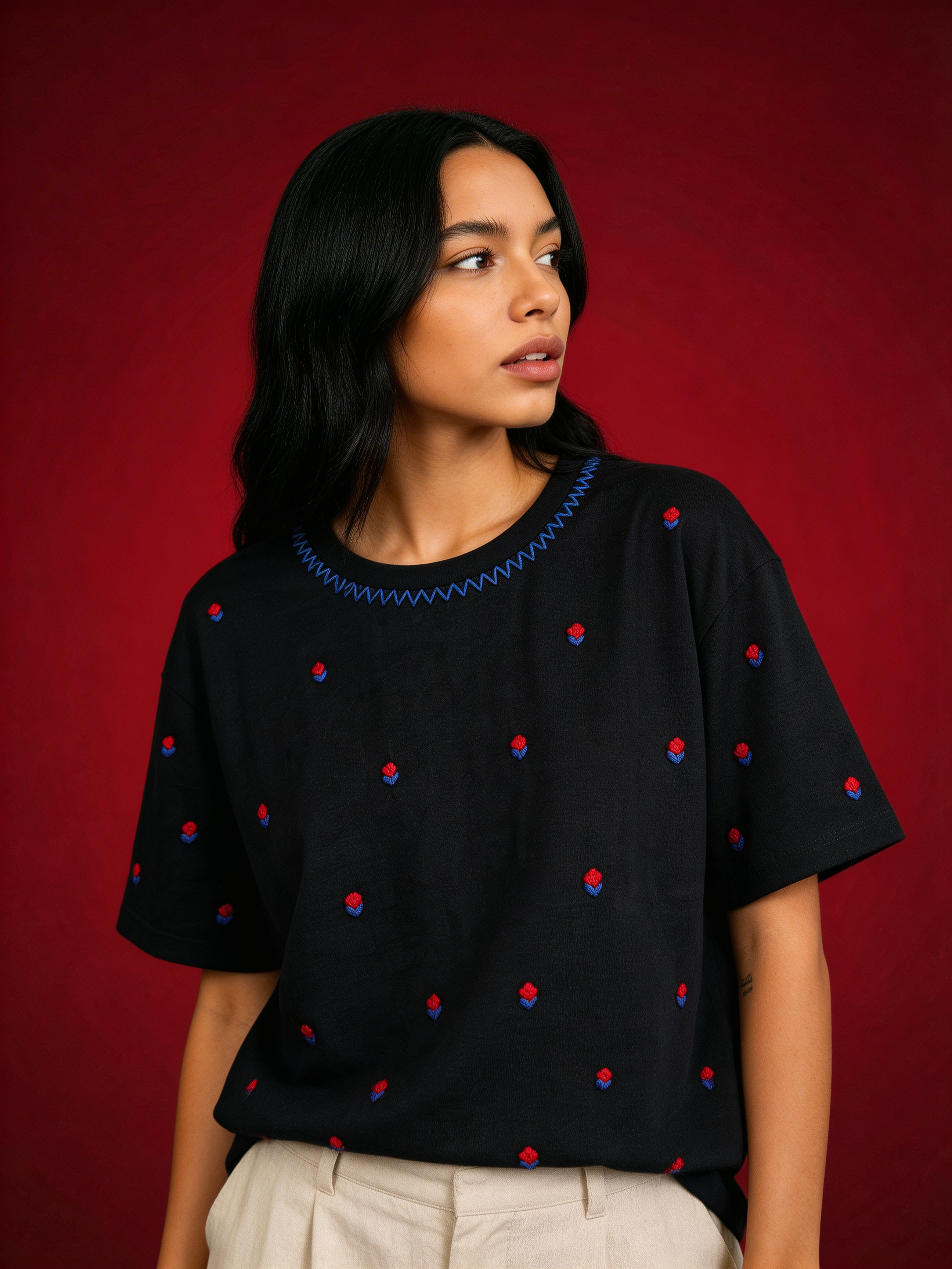 Woman wearing a black top with red and blue polka dots against a red background