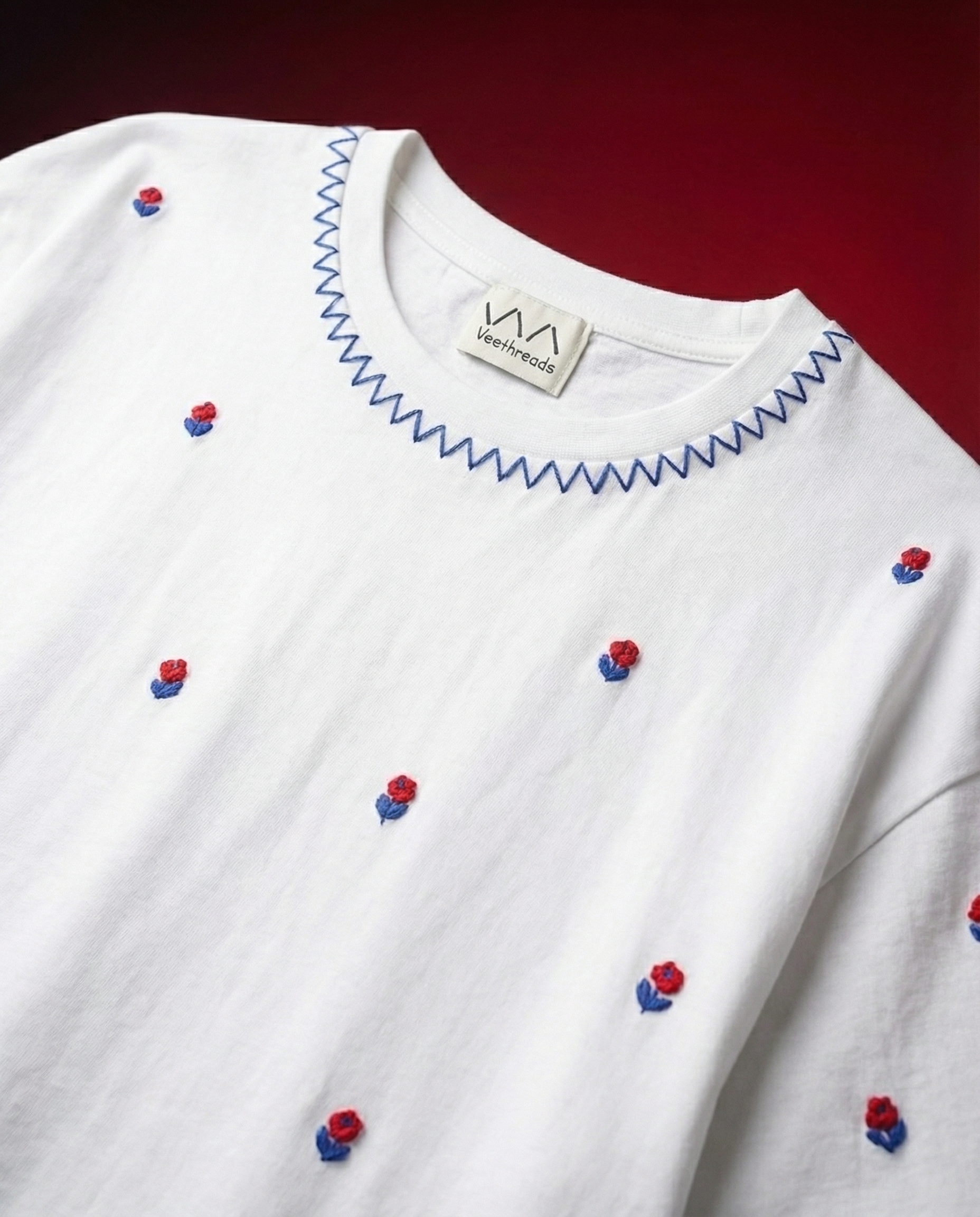 Cherry Blossom hand embroidered black t-shirt with scattered red rose buds and blue zigzag neckline stitch by Veethreads