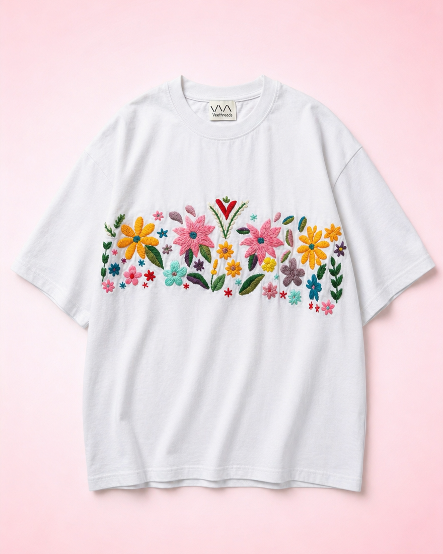 White t-shirt with colorful floral embroidery on a pink background