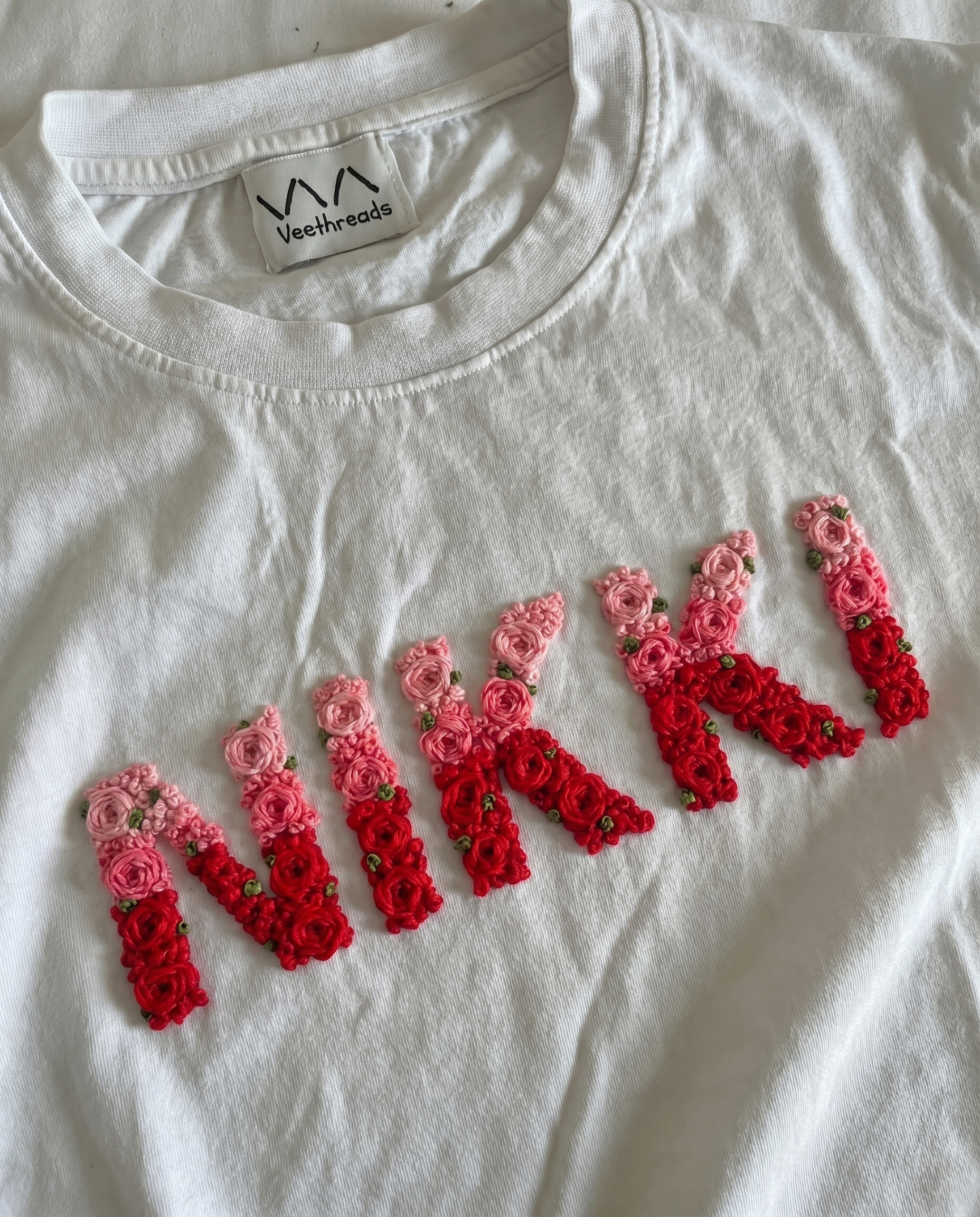 Custom name embroidered double-shade tee — white cotton tee with hand-embroidered floral text design in two thread shades, premium cotton