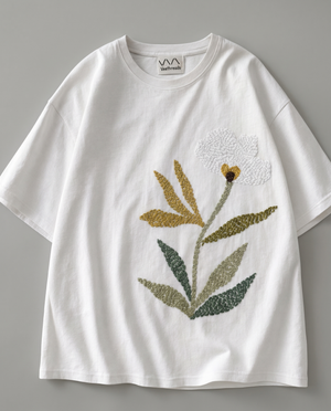 hand embroidered botanical bloom on The Botanist Tee by Veethreads — white cotton with mustard, olive and sage green stitching