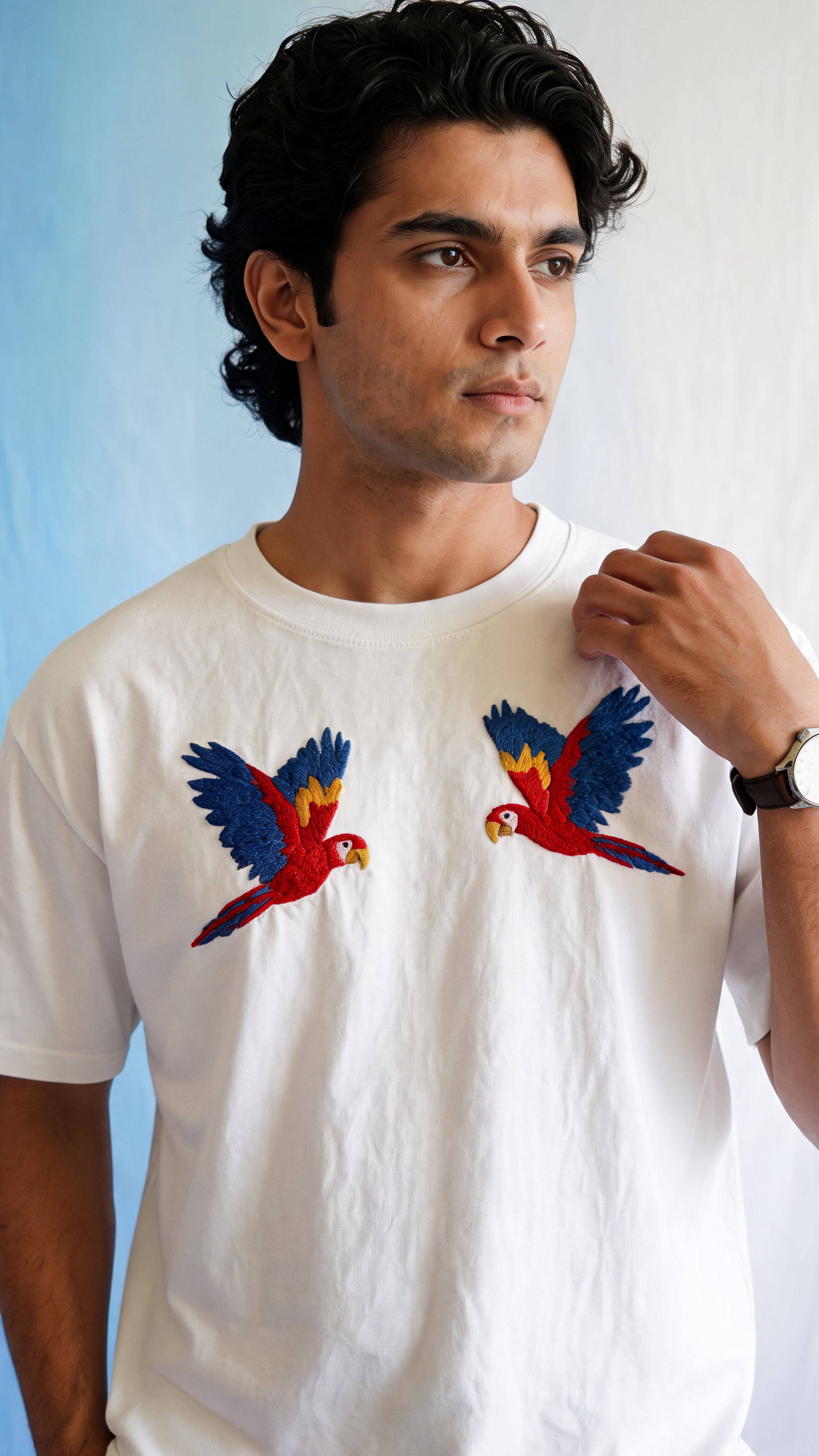 Man wearing a white t-shirt with parrot designs against a light blue background