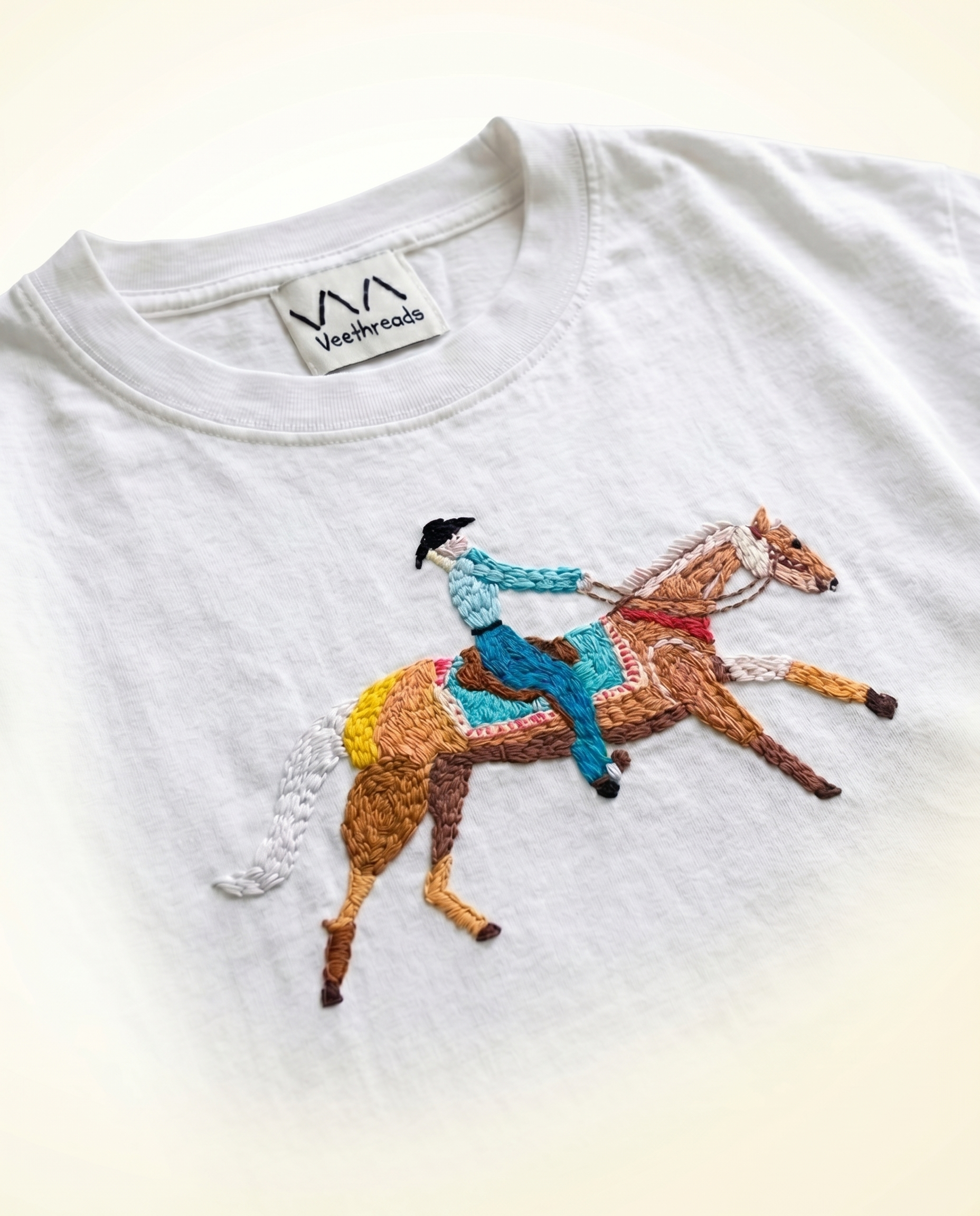 Hand-embroidered cowboy riding a palomino horse, in colourful cotton thread on a white t-shirt — Vee Threads