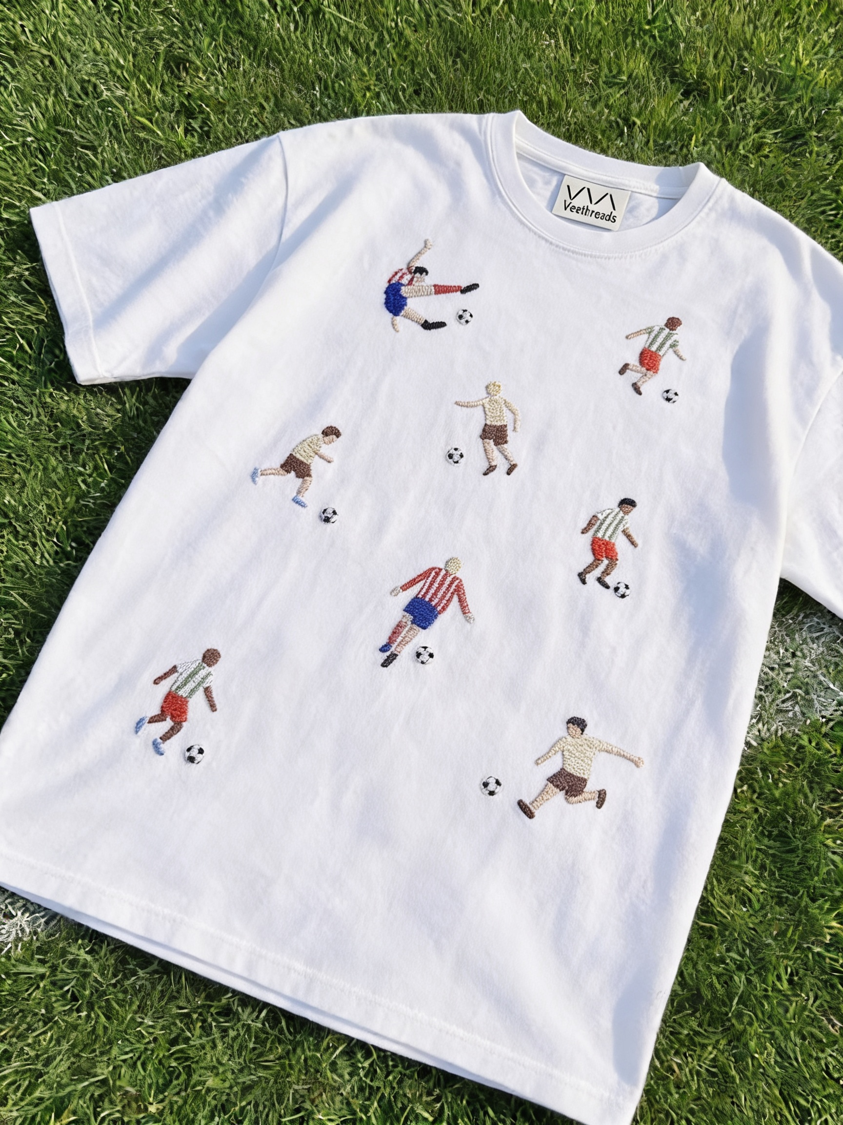 White hand-embroidered football t-shirt with eight footballers and soccer balls stitched across the front, by Vee Threads
