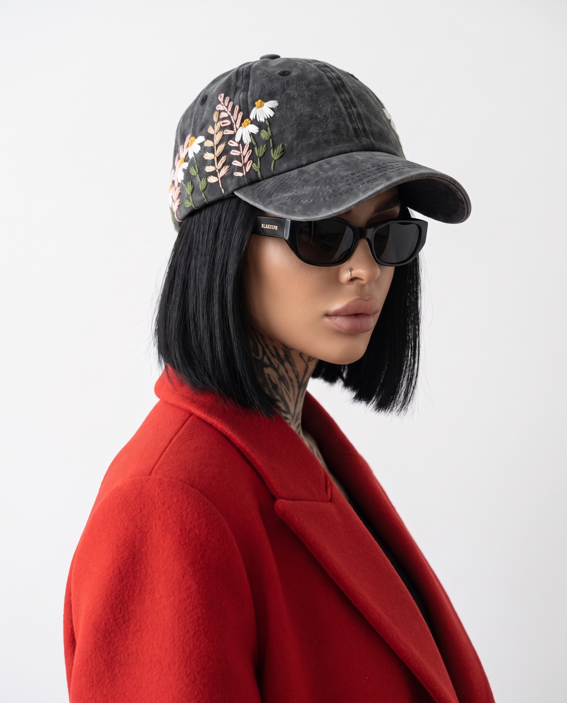 Model wearing Vee Threads desaturated floral hand-embroidered acid-wash denim cap, front view with muted faded flowers