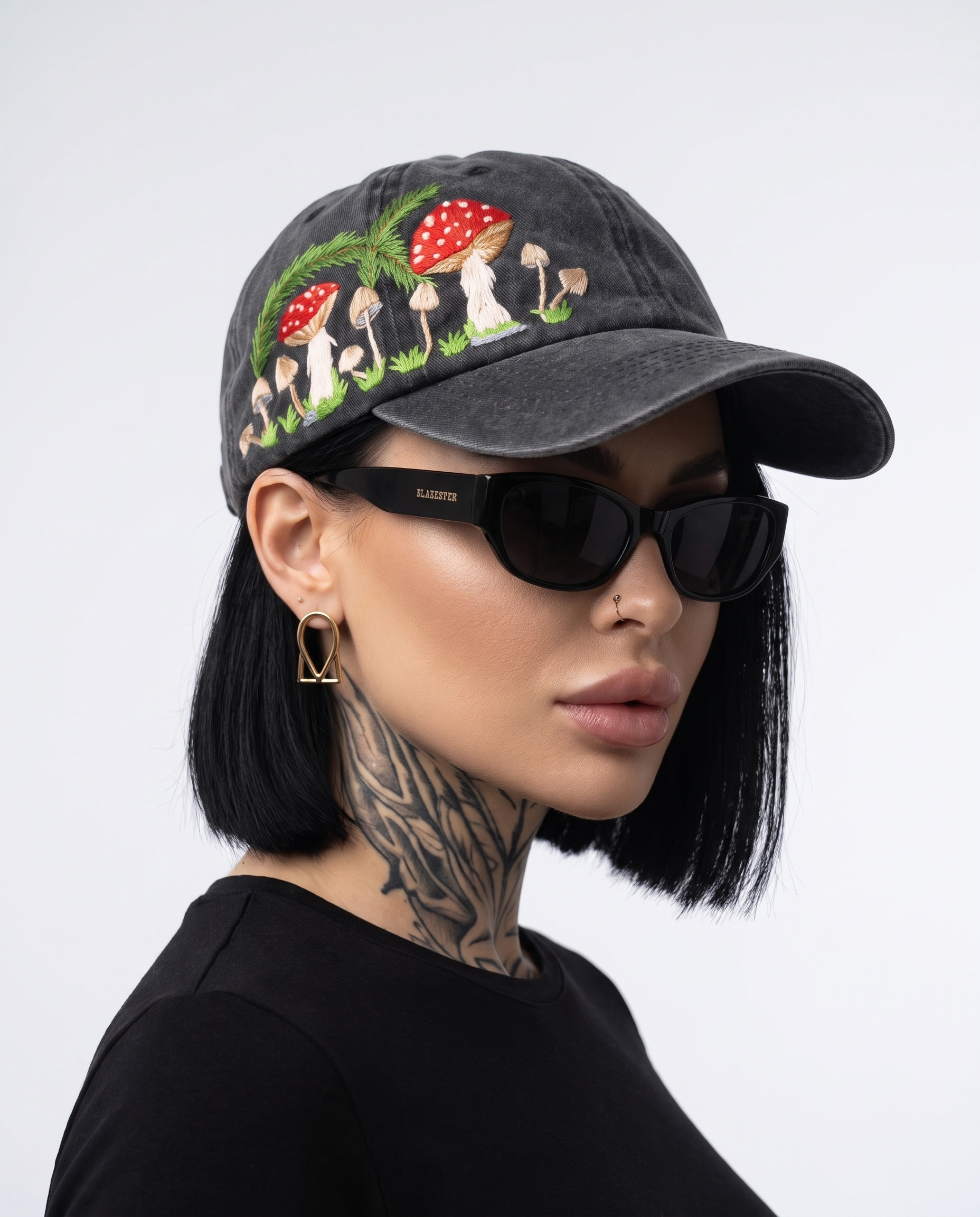 Model wearing Vee Threads meadows mushroom hand-embroidered denim cap, front view with toadstools, grass and pine