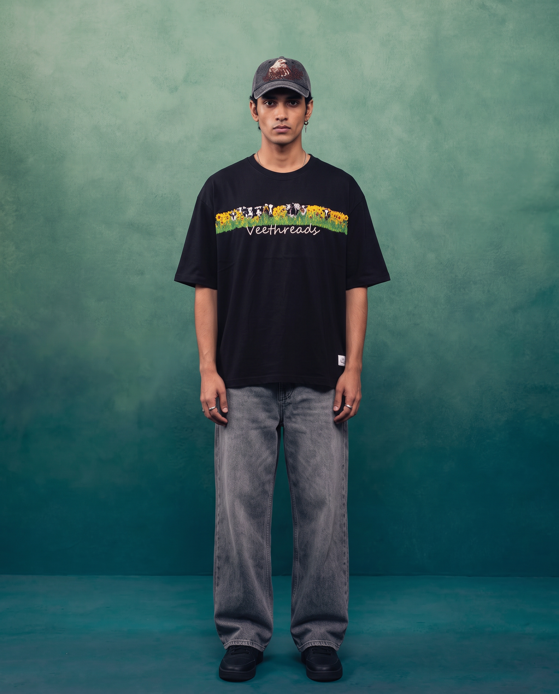 Man wearing black hand embroidered oversized t-shirt for men with cow and sunflower meadow embroidery