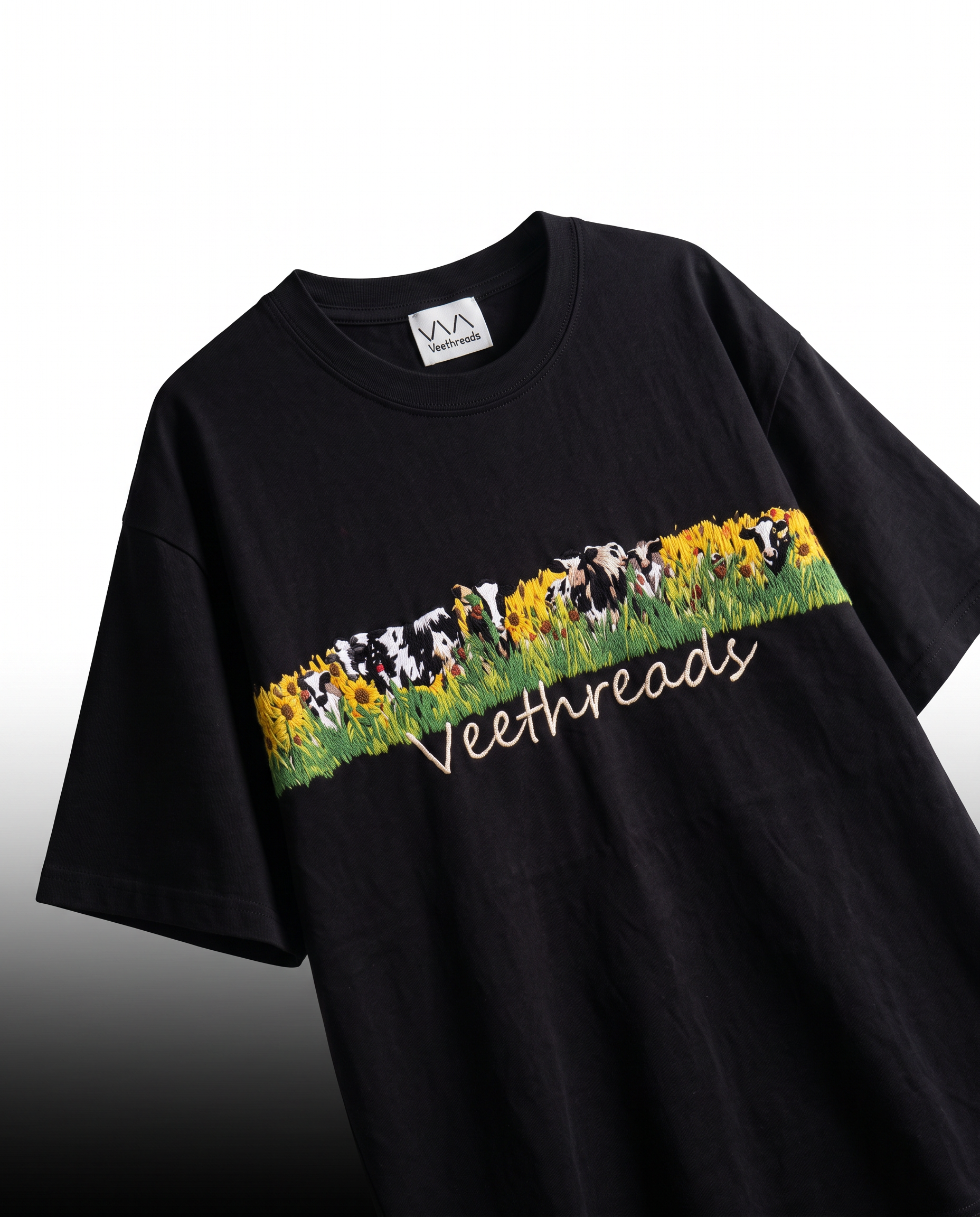 Angled view of black embroidered t-shirt showing raised thread work in the sunflower meadow band