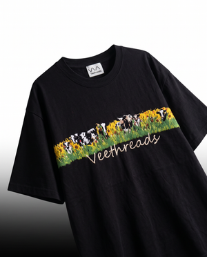 Angled view of black embroidered t-shirt showing raised thread work in the sunflower meadow band