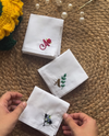 Three personalised embroidered handkerchiefs with hand stitched initials in pink, gold and navy thread on white cotton