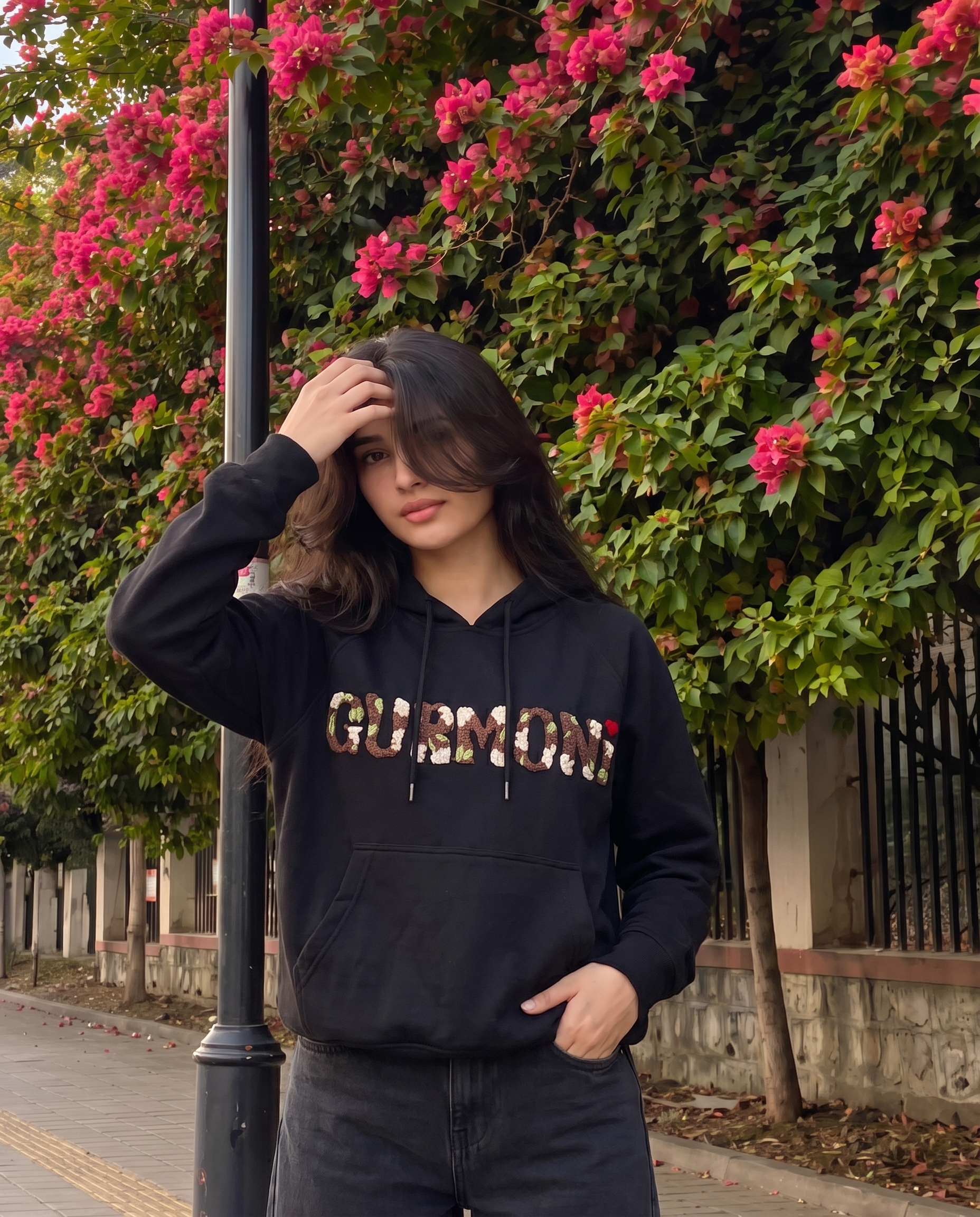 Black personalised hoodie with hand embroidered name worn outdoors, oversized fit