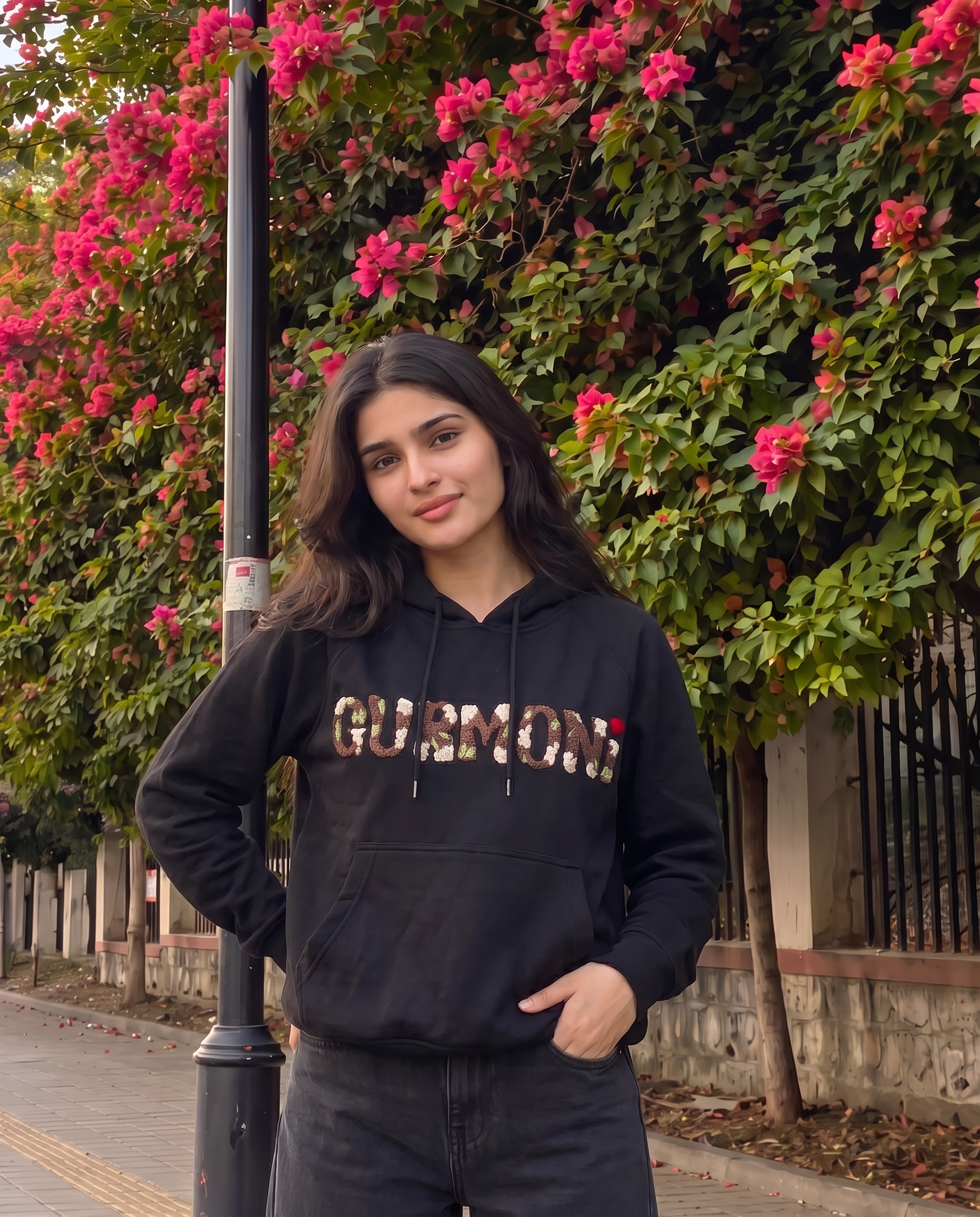 Woman wearing a black embroidered hoodie with her name hand stitched in floral letters