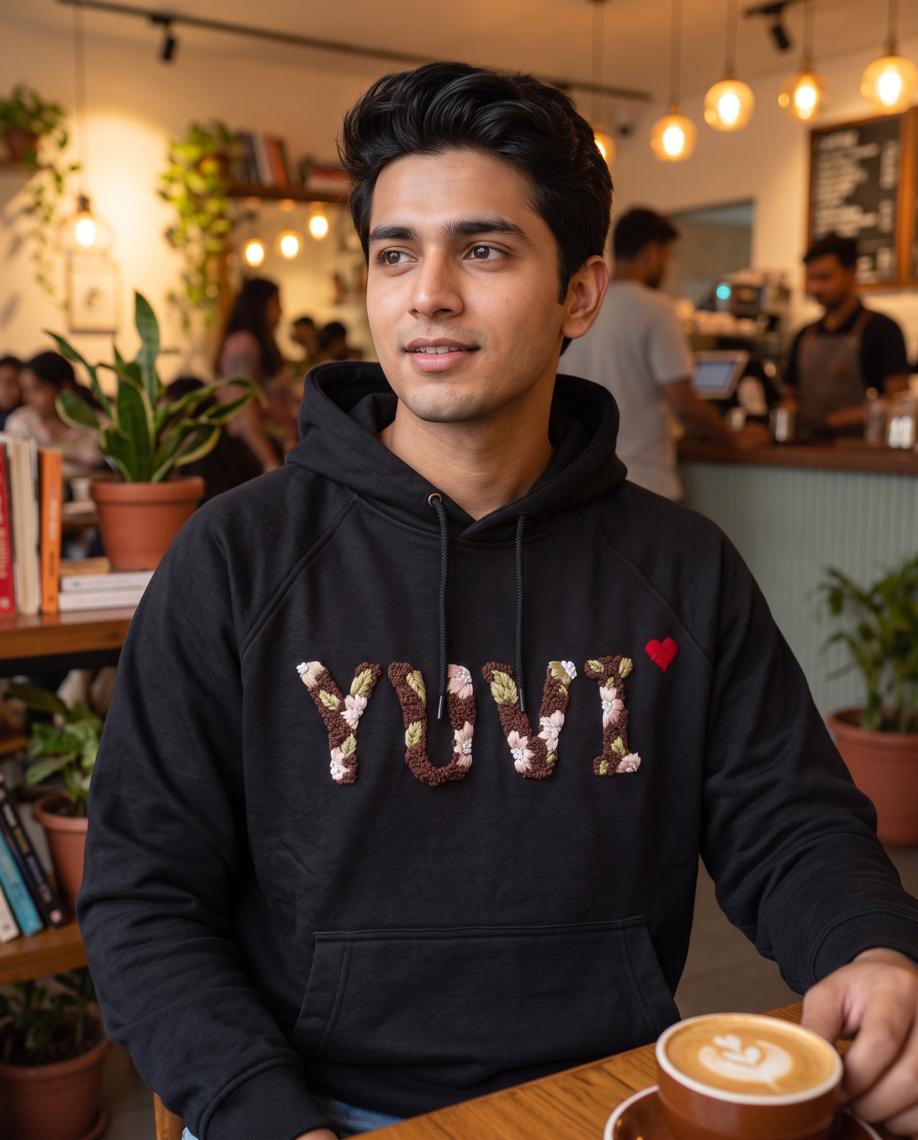 Man wearing a custom name embroidered hoodie in black cotton fleece with floral lettering