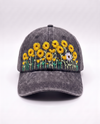 Charcoal acid-wash denim cap, front view, with a row of hand-embroidered yellow sunflowers and one white daisy