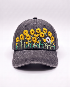 Charcoal acid-wash denim cap, front view, with a row of hand-embroidered yellow sunflowers and one white daisy