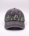 Charcoal acid-wash denim cap, front view, with white lily of the valley bells and two embroidered bees above them