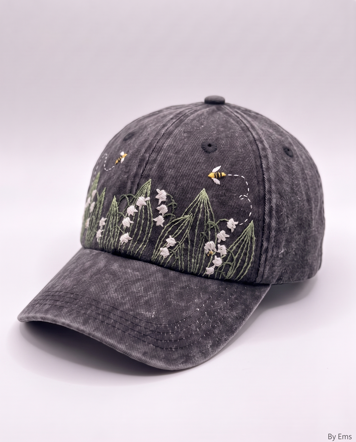 Angled view of the lily of the valley cap showing the curved brim and the embroidery wrapping toward the side panel