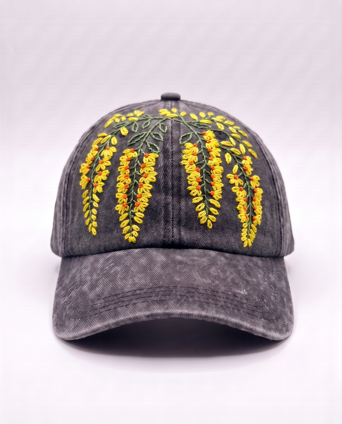 Charcoal acid-wash denim cap with yellow amaltas blossom sprays hand-embroidered down the crown, front view
