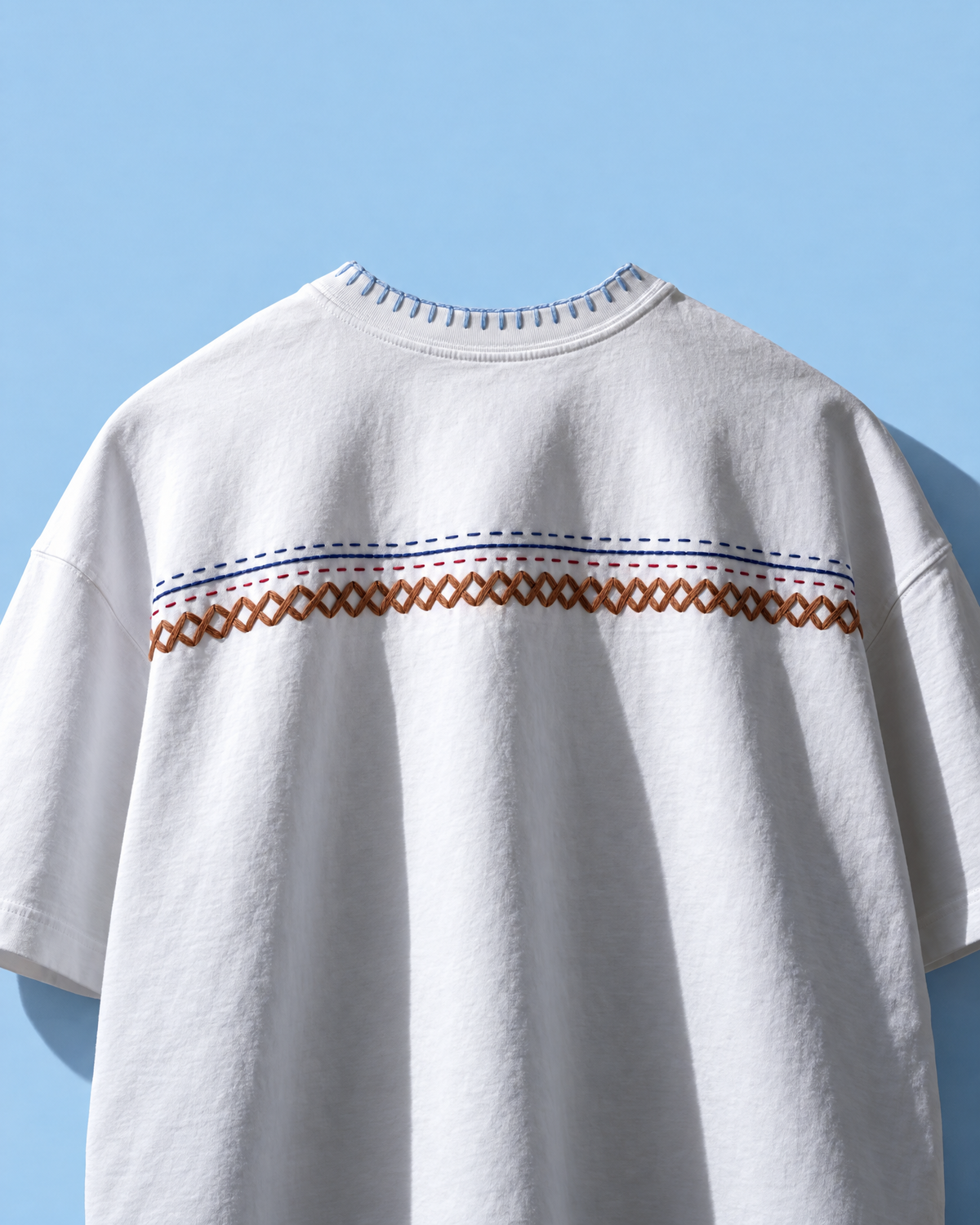 White oversized kantha stitch t-shirt with running stitch rows and a brown herringbone band across the chest
