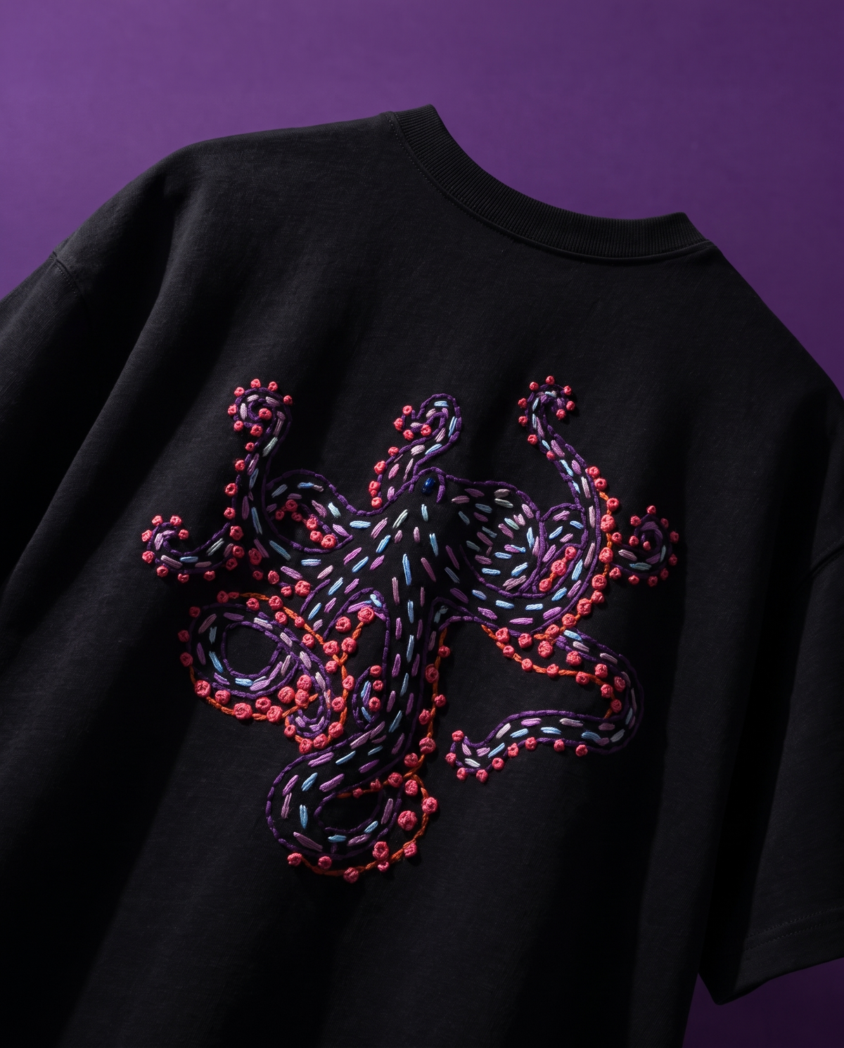 Black octopus embroidered t-shirt, back view, octopus in purple, pink and blue thread with coral French knots