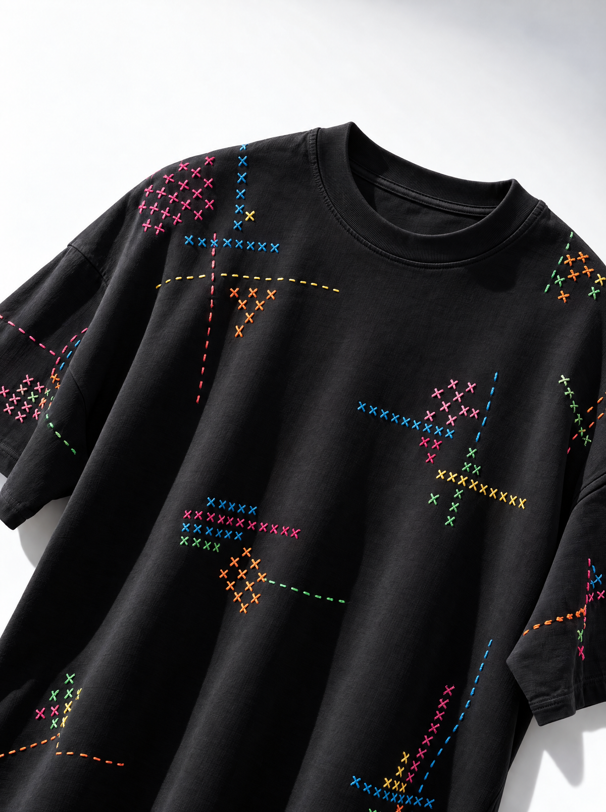 Angled view of the cross stitch embroidered black t-shirt showing stitching on the shoulder and sleeve