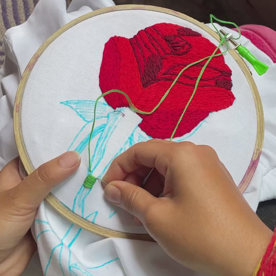women doing  a large hand-embroidered red rose and green stem design on the front.